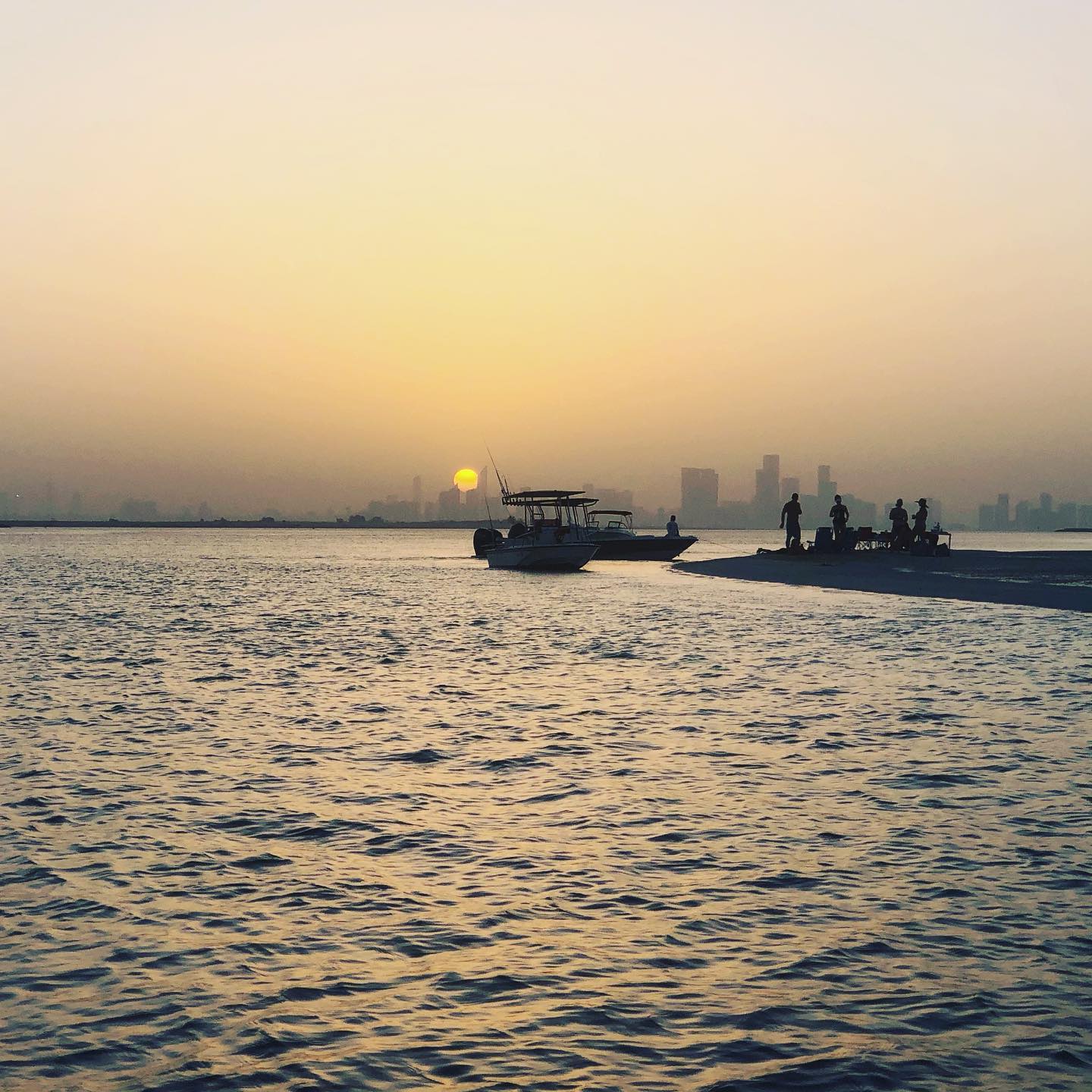 Sunset over city from a sandbar in the sea.