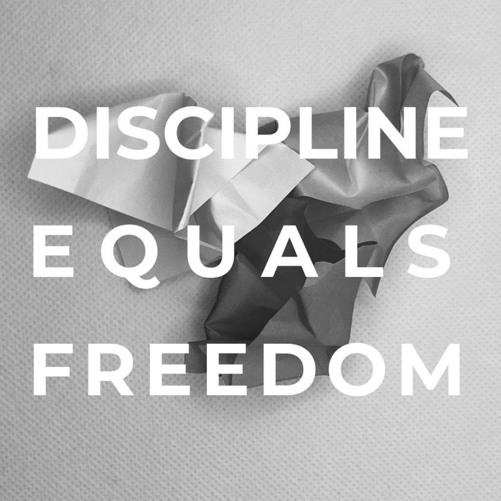 Discipline Equals Freedom over background of crumpled sticky notes.