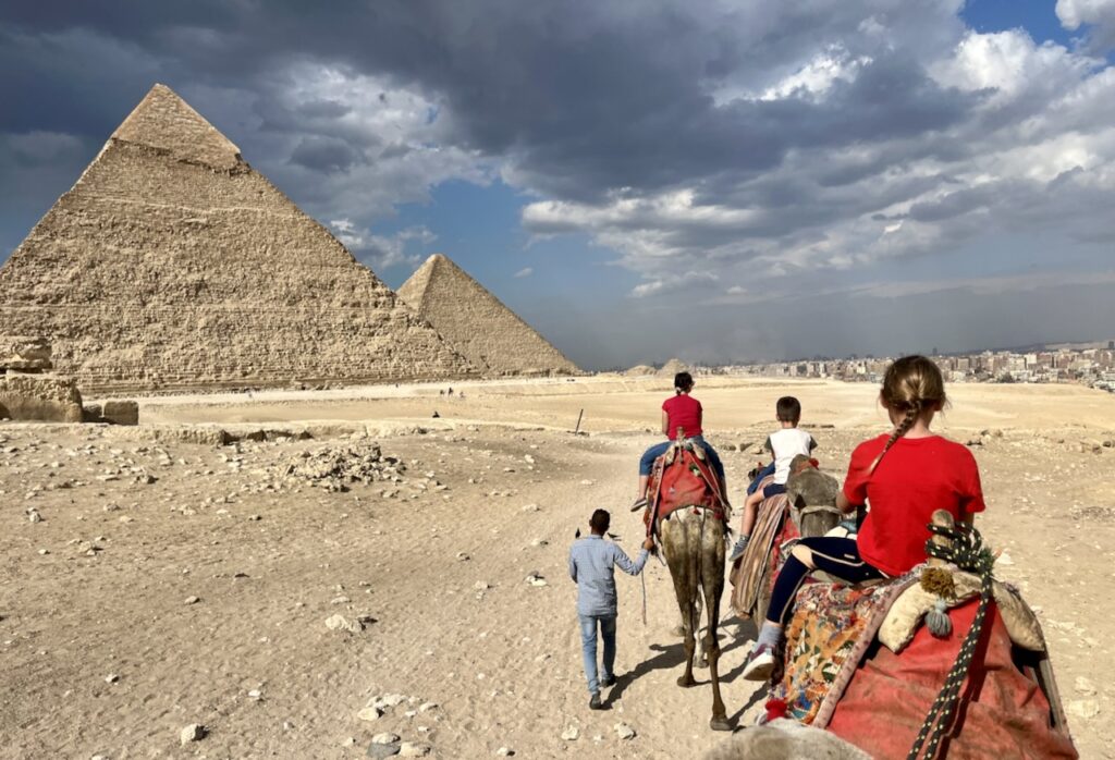 Family on camels heading towards Giza pyramids.