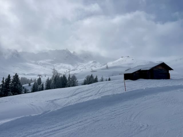 Hut in snow sunny / cloudy sky.